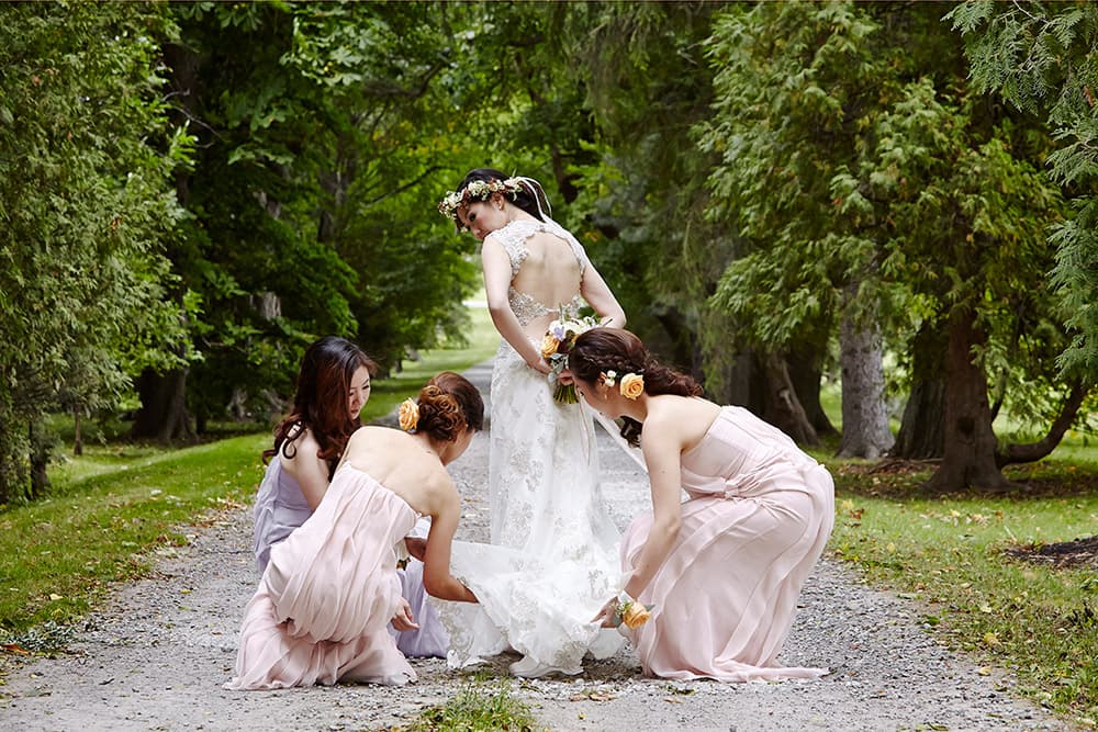 Kurtz Orchards wedding photograph of bridal party bridesmaids finishing brides dress outdoor wedding Niagara-on-the-lake